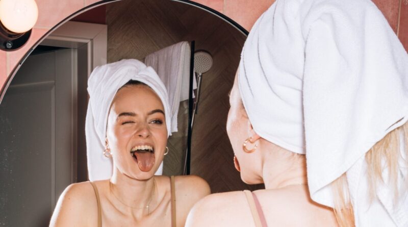 girl with towel in hair sticking tongue out in mirror