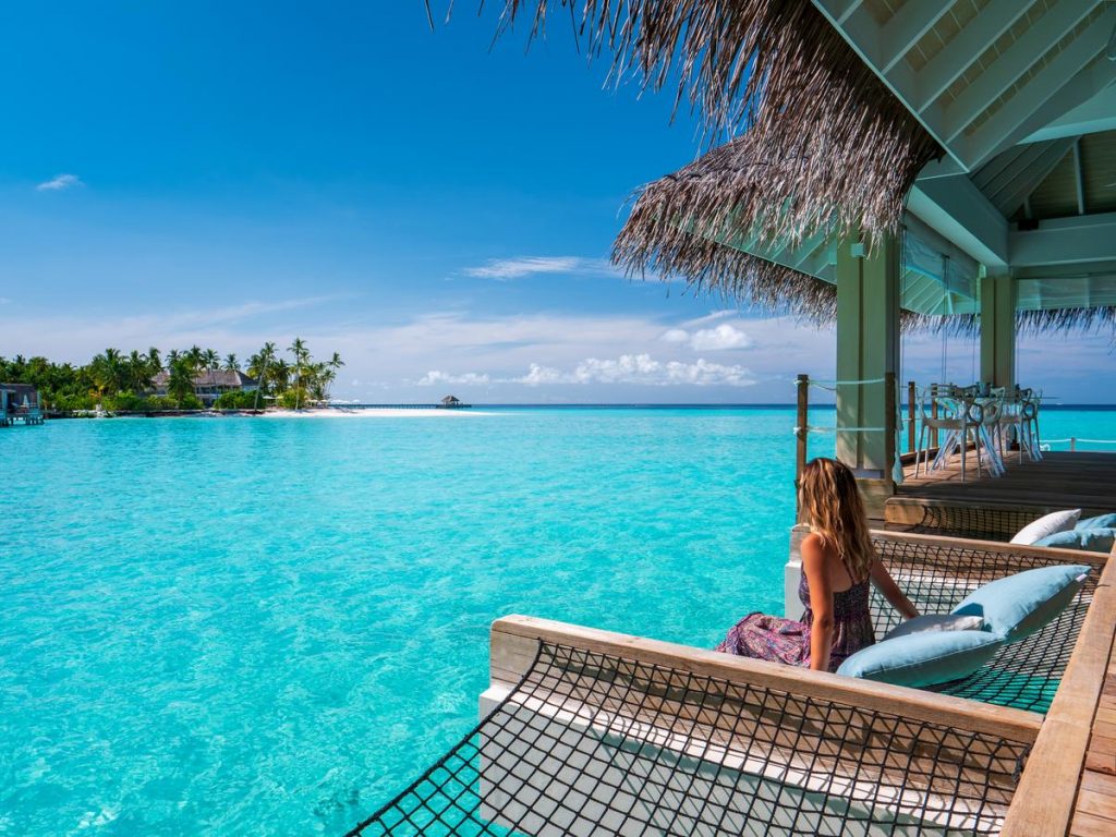 girl sitting on hammock overlooking maldives villas at baglioni resort restaurant luxury hotels and resorts in maldives