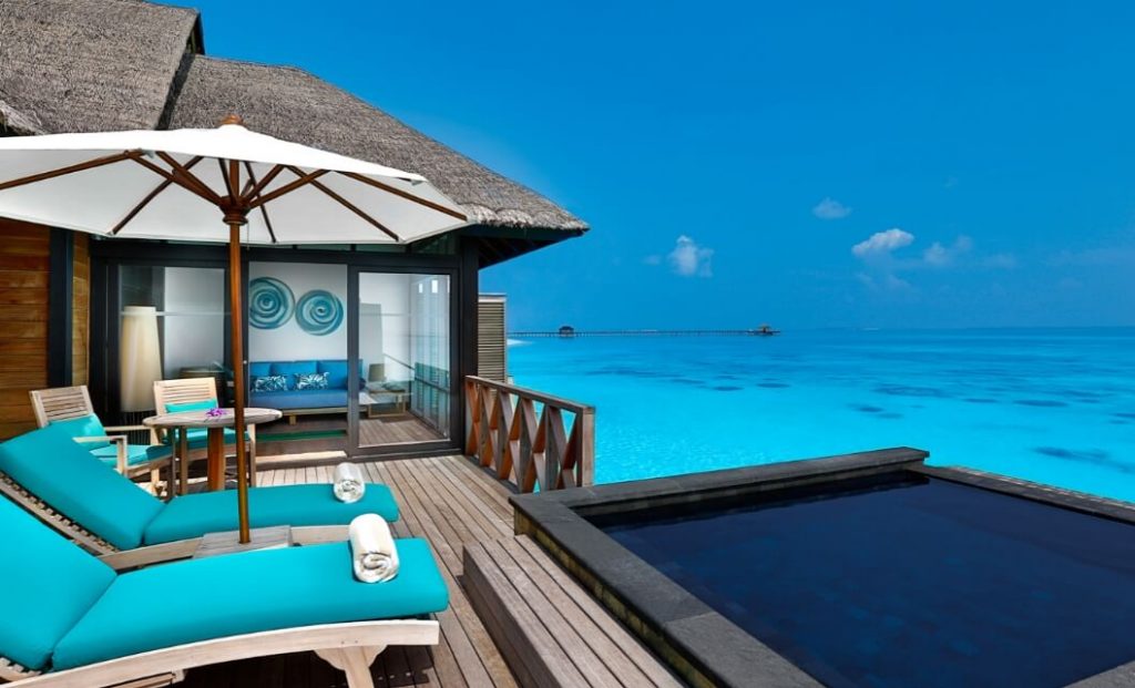 maldives over water villa with infinity pool deck with blue sun loungers facing a blue lagoon