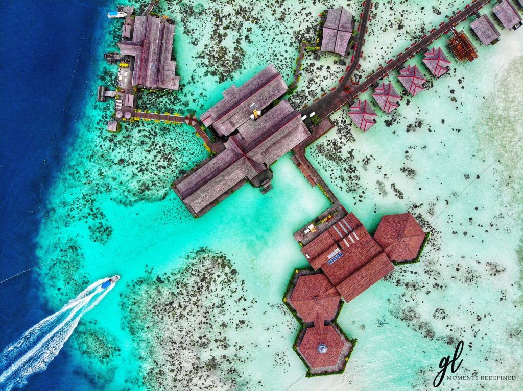 aerial view of sipadan kapalai beach resort wooden chalets and surrounding deep blue sea and turquoise lagoon with speedboat 