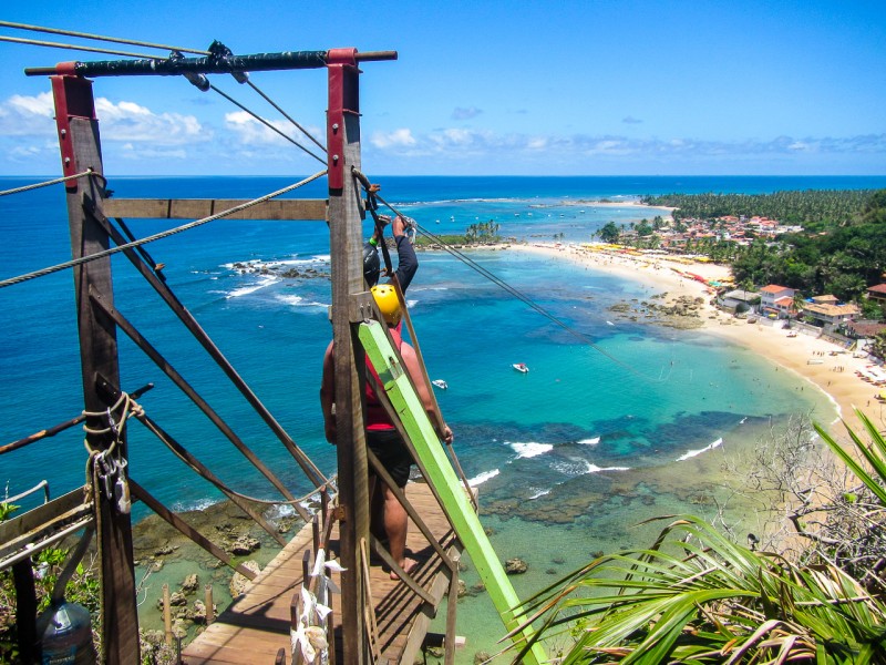 ziplining in morro de sao paolo in brazil man overlooking the beach atop a hill 