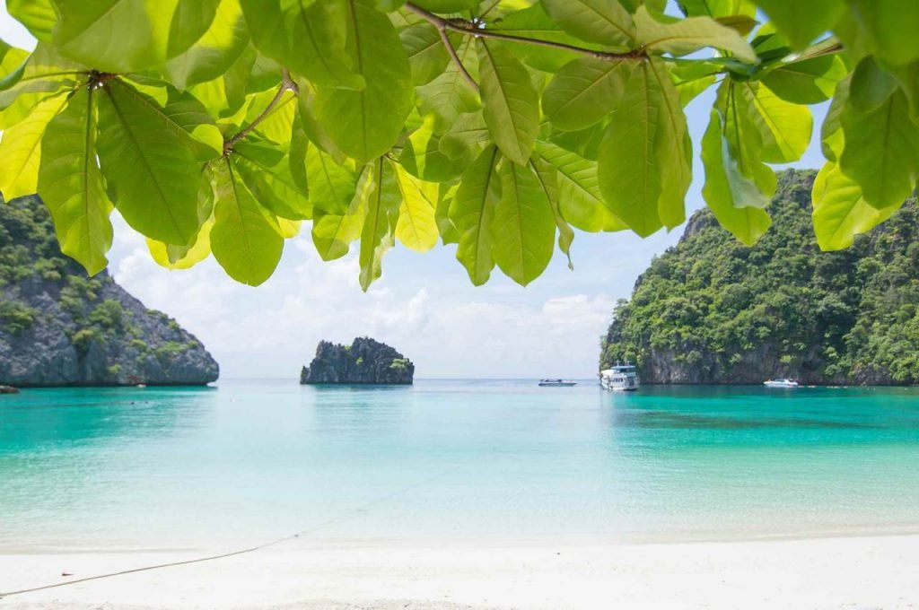 white sand beach looking out to turquiose water and tropical islands by each side