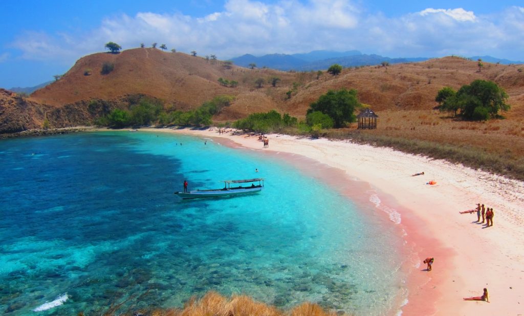 pink sand beach in lombok with azure sea and mountains