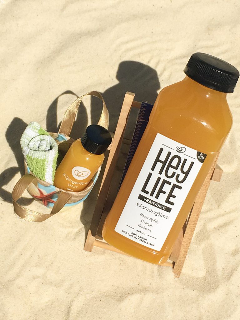 how to do a juice cleanse in summer - tanningtime heylife rawjuice and ginger shot bottle on the beach