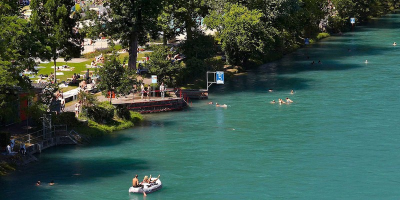 people swimming, tanning and boating in the Aare River next to Marzili 