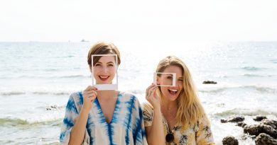 two women smiling with makeup and picture frames by the beach