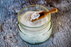 small jar of coconut oil with little wooden scoop spoon