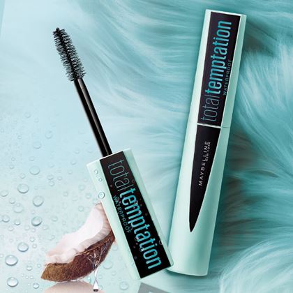 maybelline total temptation mascara with coconut piece on a blue background