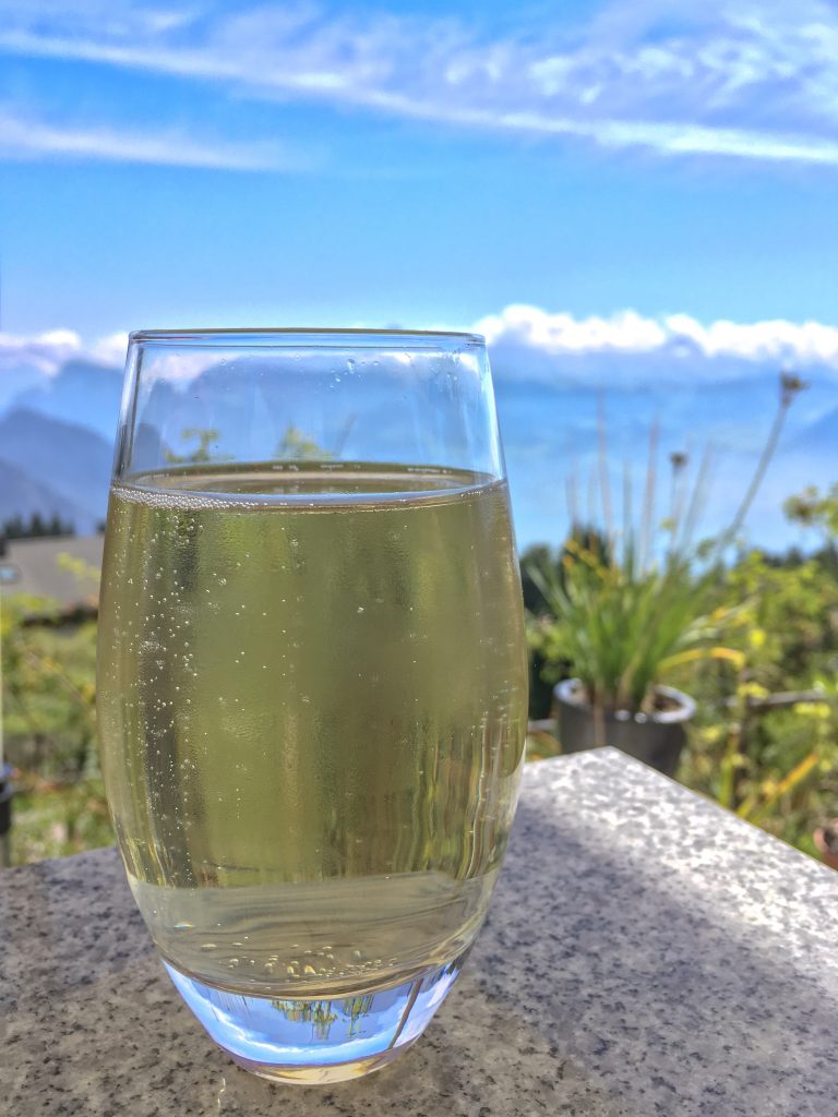 yellow rigi cola made from herbs in a clear glass with the swiss alps in the background