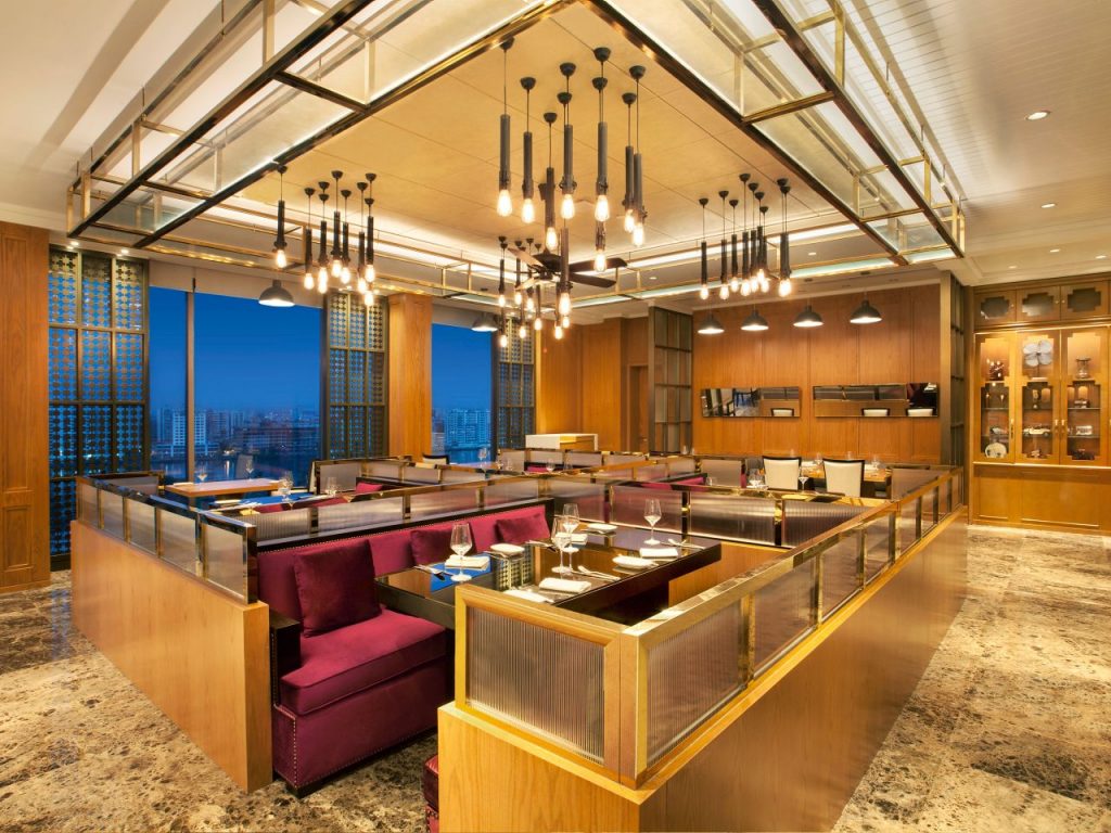 interior of the colony restaurant and grill featuring gold trimmed dining cubicles with purple velvet seats and gold chandeliers