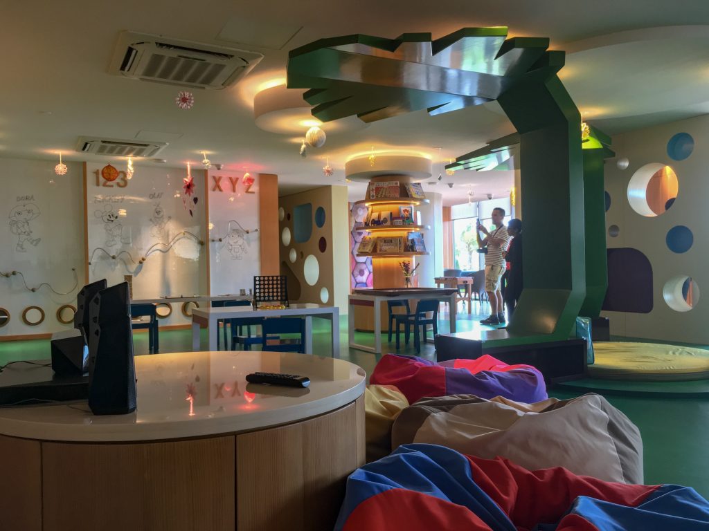 inside the kids club room with bean bags, art wall and play areas