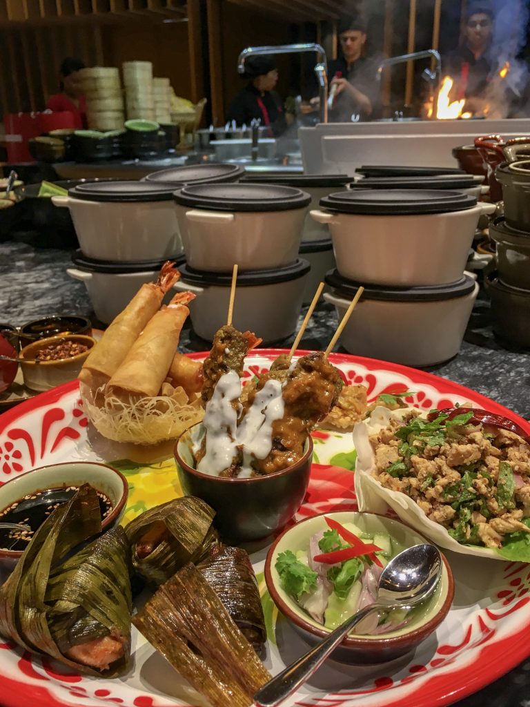 Thai food appetizer platter with pandan chicken, prawn springrolls, chicken laab, chicken satay skewers and sauces