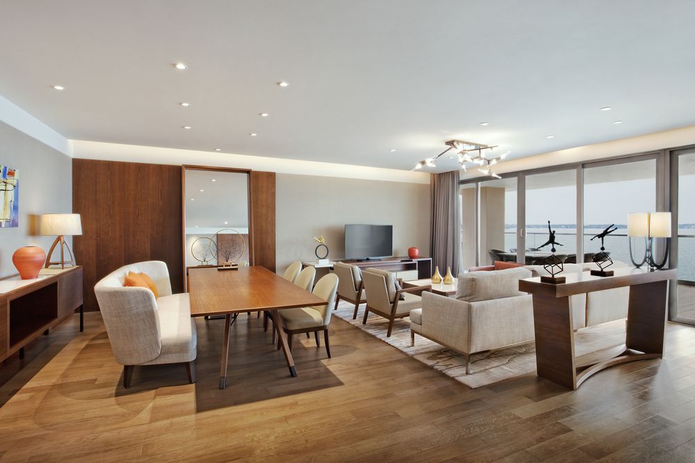 Modern deco with light wooden floors, dining and living area with white chairs and wooden tables inside the executive suite