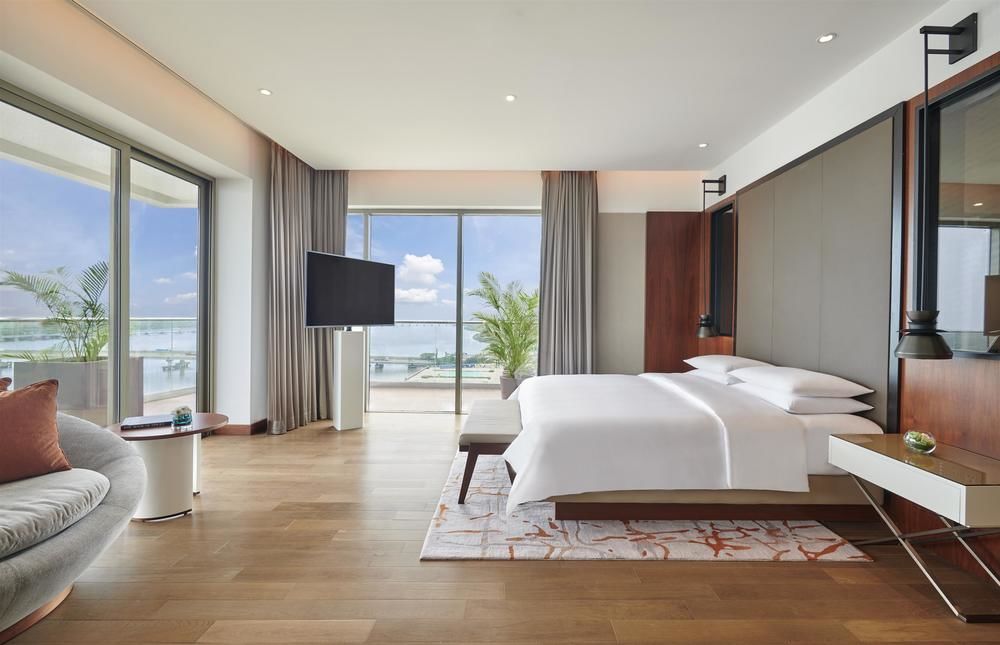 terrace suite with floor to ceiling windows on two sides and king bed in grand hyatt kochi suite