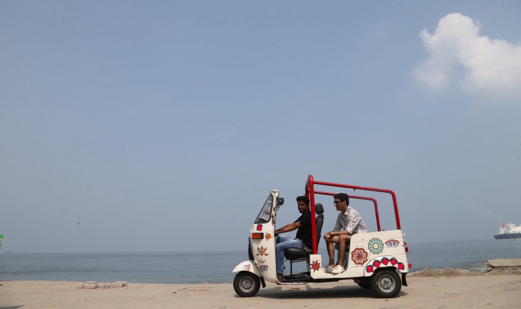 white tuk tuk riding across fort kochi beach with passenger