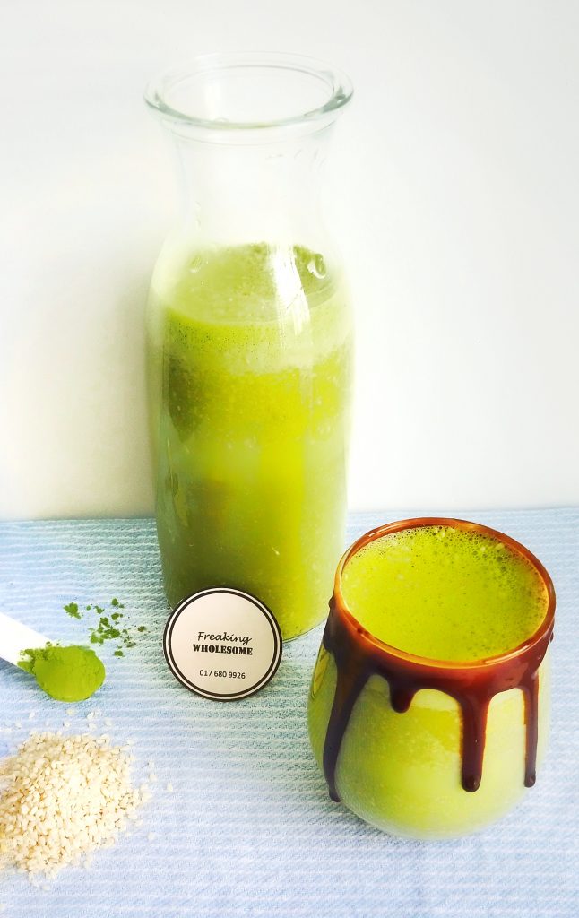 energizing matcha sesame milk jar filled with drink and cup with white sesame seeds and matcha powder at the side