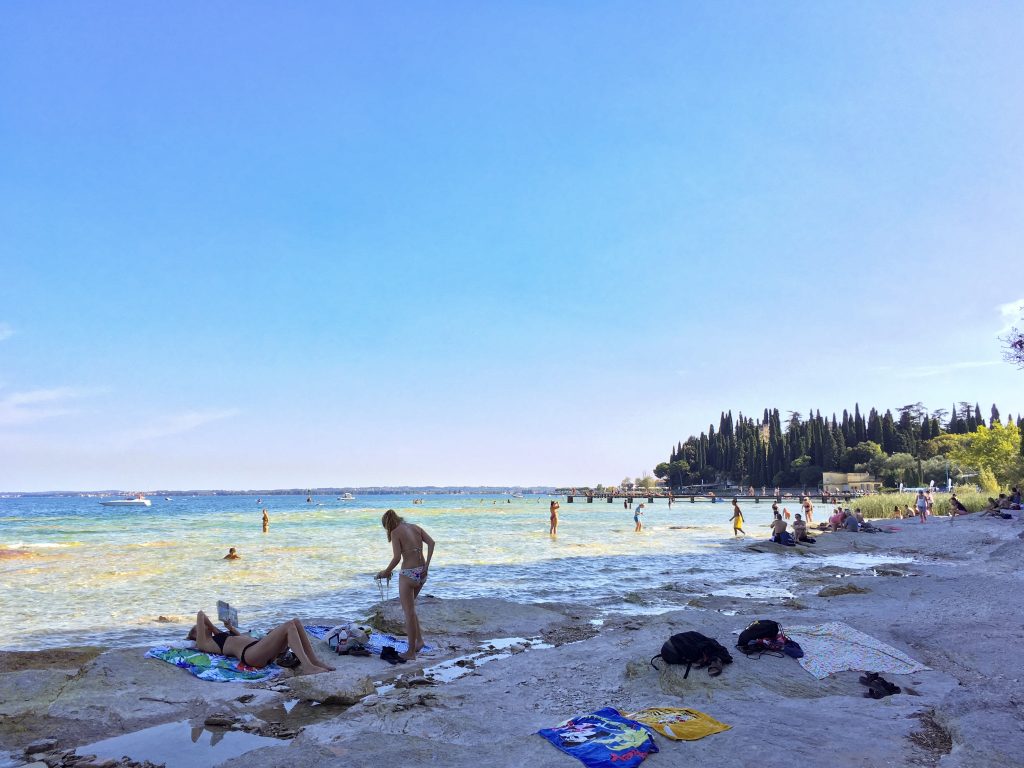 Women in bikini sunbathing and relaxing on rocks on Lido della Bionde beach
