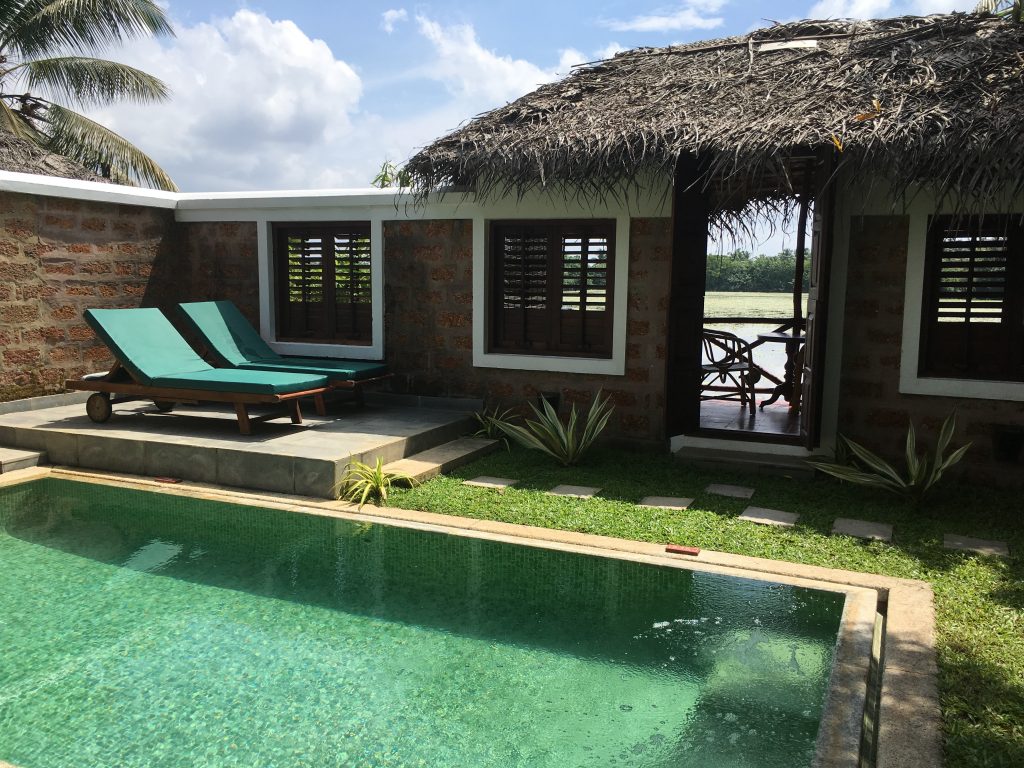 private pool with two green sun loungers and a private terrace with thatched roof facing the lake