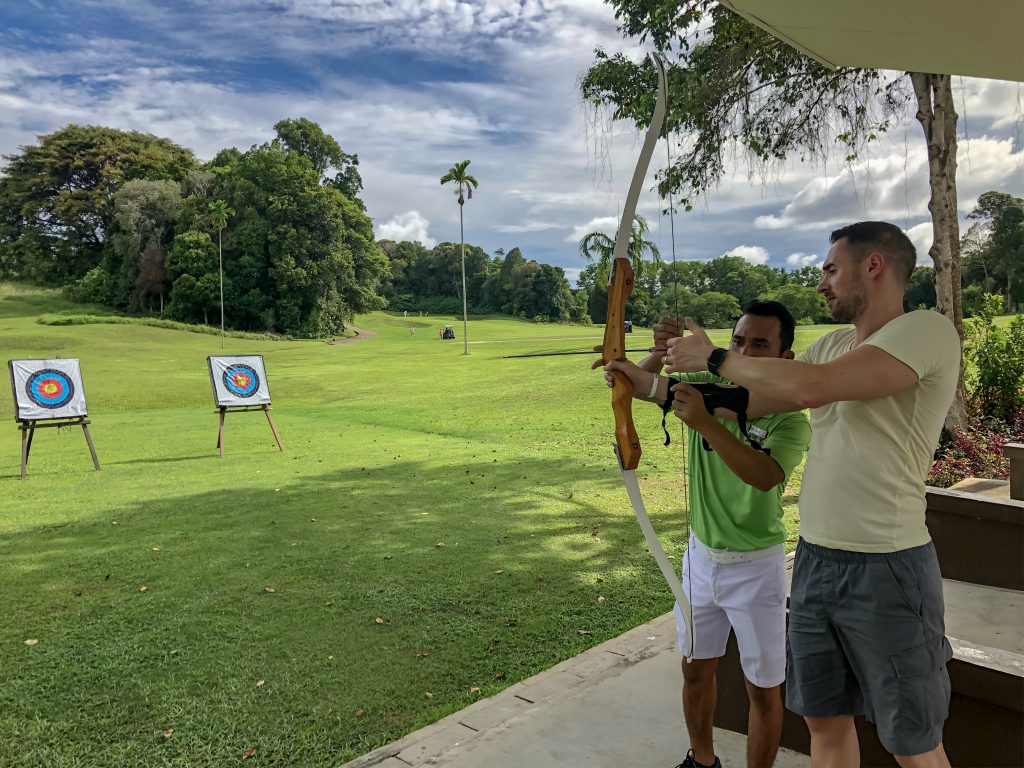 instructor teaching man archery lessons with bow and arrow