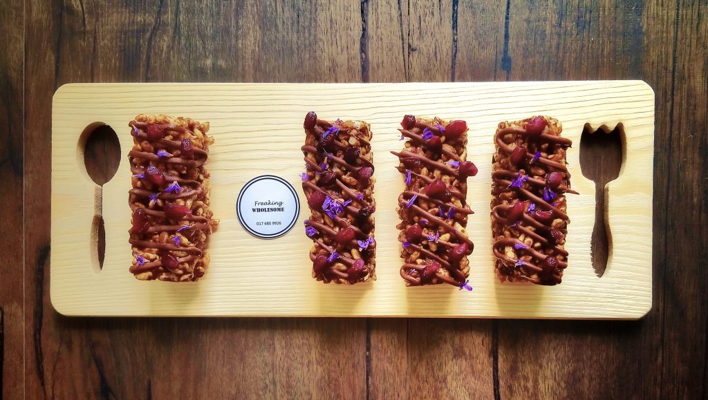 crunchy chocolate tahini slice on a wooden platter decorated with chocolate drizzle and edible flowers