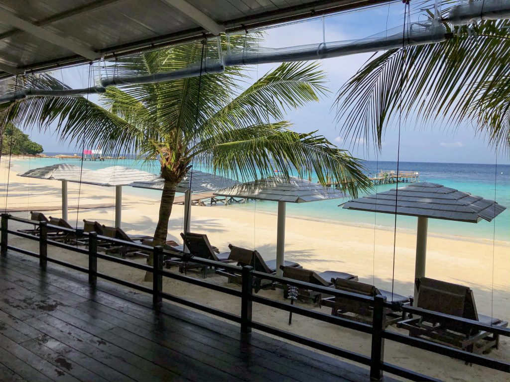 seaview cafe seating area with sun loungers overlooking white sandy beach and azure sea at summer bay lang tengah island