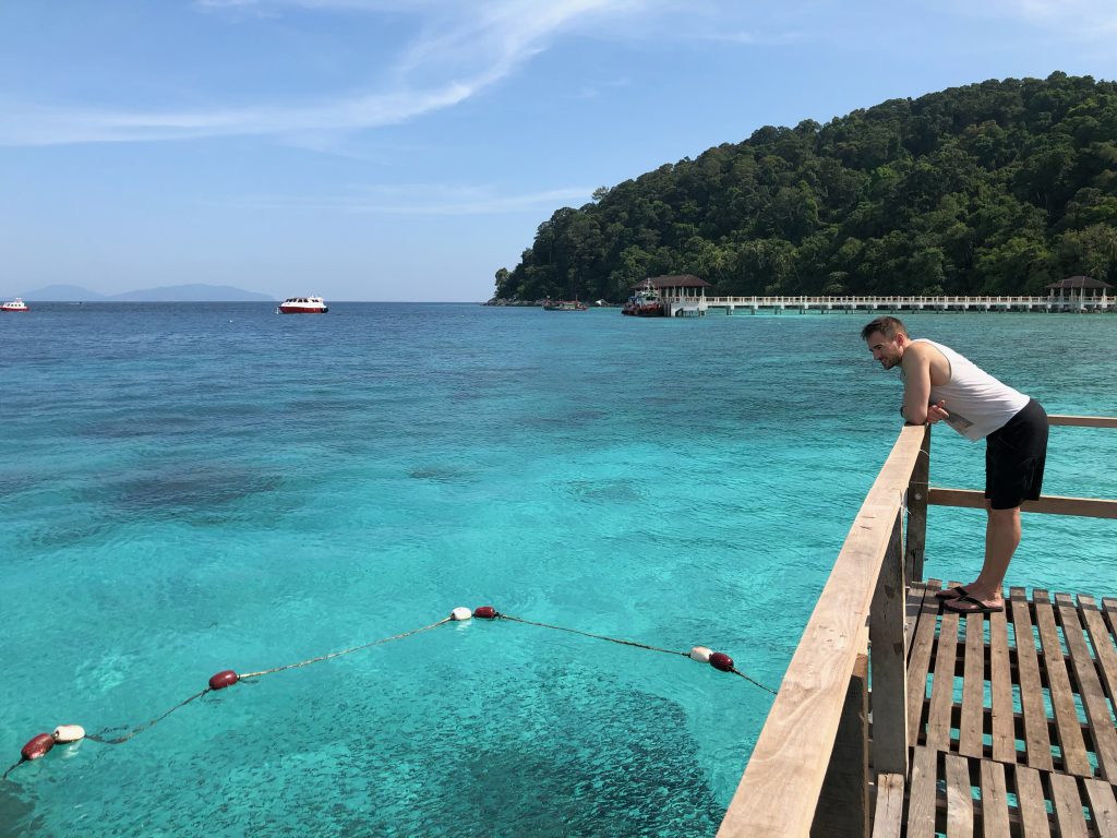 man looking down at coral reef from the boardwalk pier