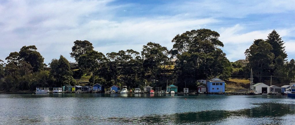 colourful timber boat sheds lined up along Forsters Bay Narooma Australia