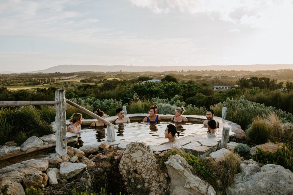 group of adults in natural hot springs pool surrounded by greenery and hills