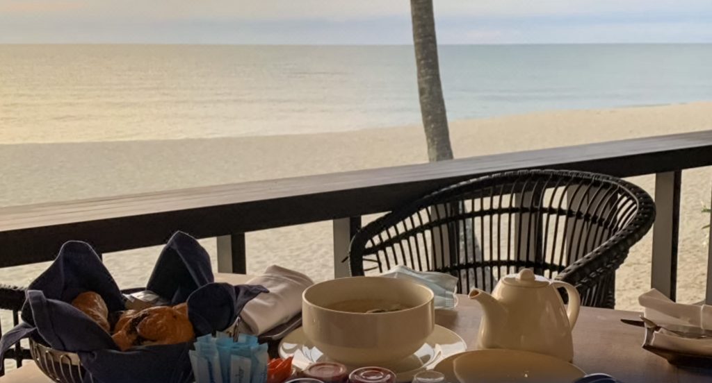 basket of pastries, coffee pot, breakfast jams on a table overlooking teluk cempedak beach at kampung restaurant hyatt