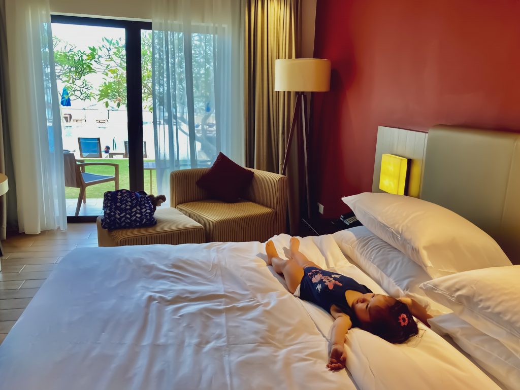baby girl stretching out on hotel bed 