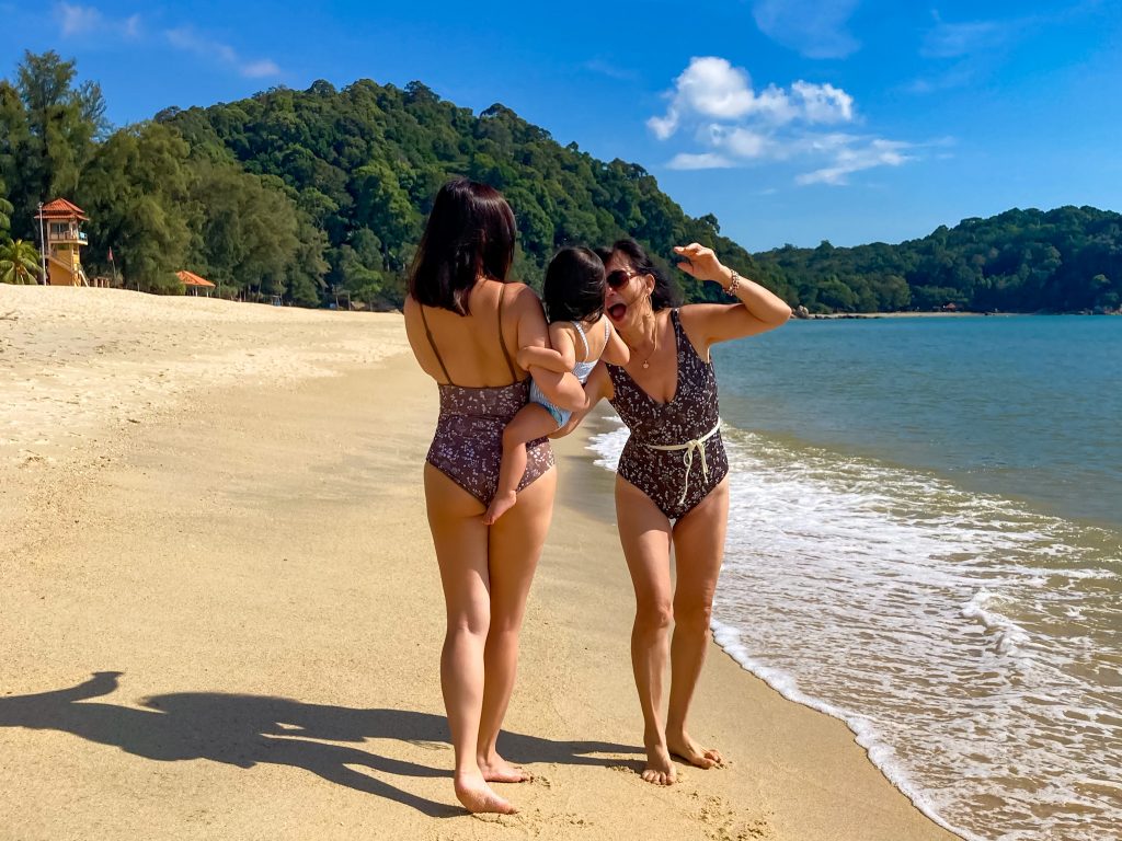 grandmother, mother and baby on beach in matching swimwear