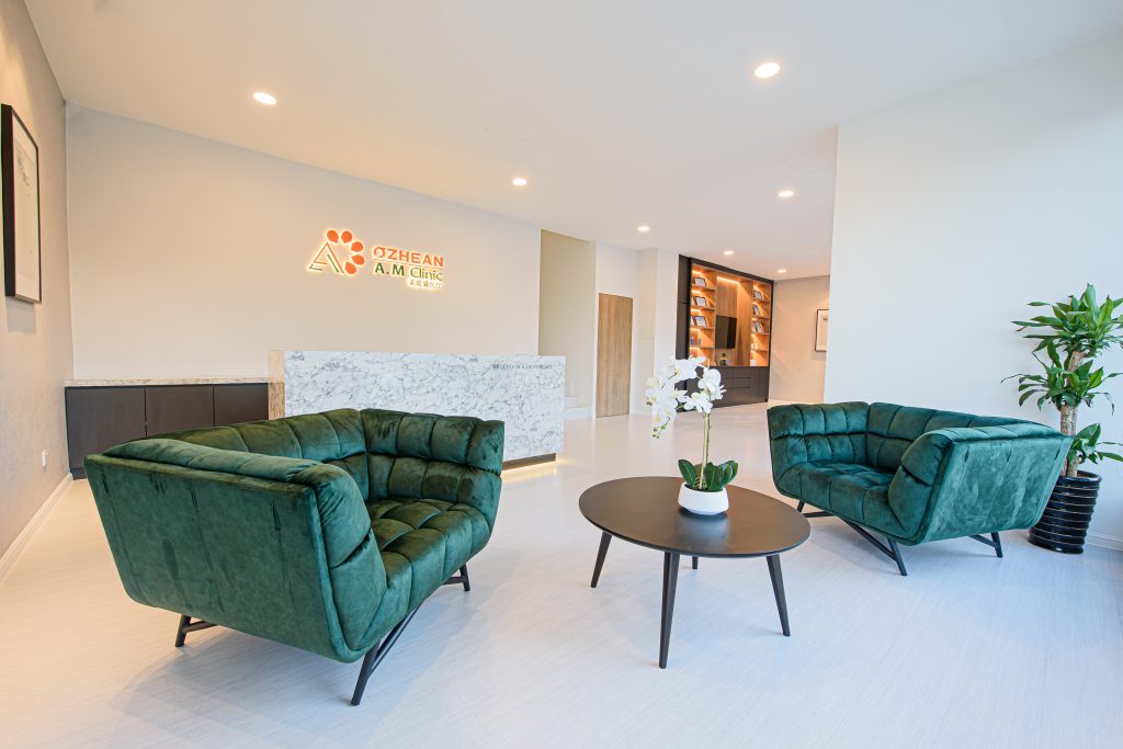 reception area of ozhean clinic bangsar branch with velvet green chairs and white interior